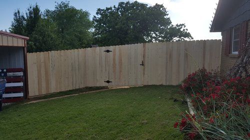 A wooden fence with a gate in the backyard of a house.