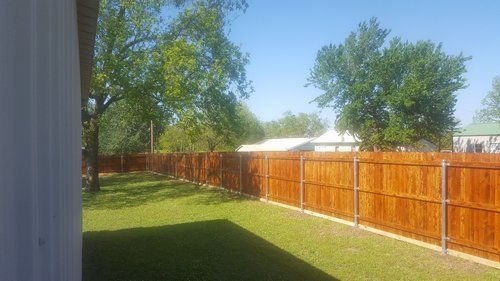 A wooden fence is in the backyard of a house.