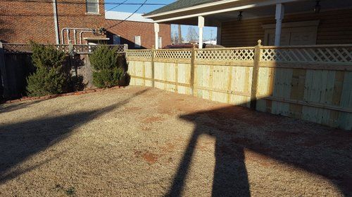 A wooden fence is in the backyard of a house.
