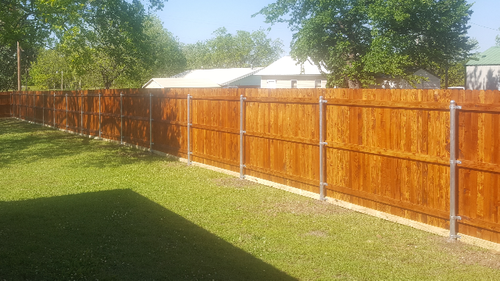 A wooden fence is sitting in the middle of a lush green yard.