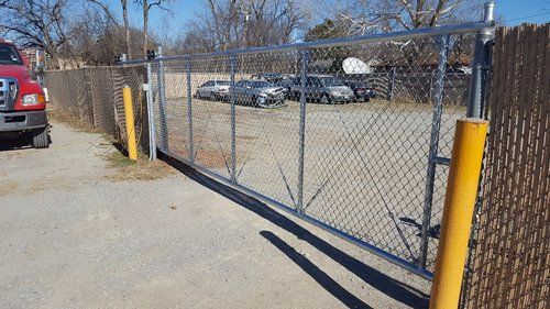 A red truck is parked in front of a chain link fence.