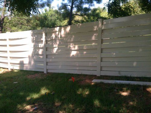 A white wooden fence is sitting in the middle of a lush green field.