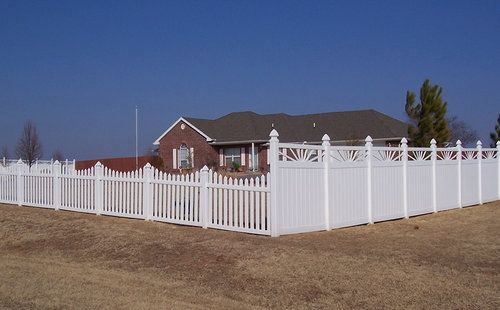 A white picket fence surrounds a brick house