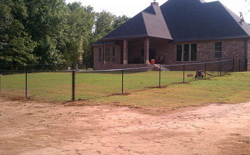 A large brick house with a chain link fence in front of it