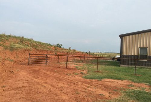 A dirt road leading to a building with a gate.