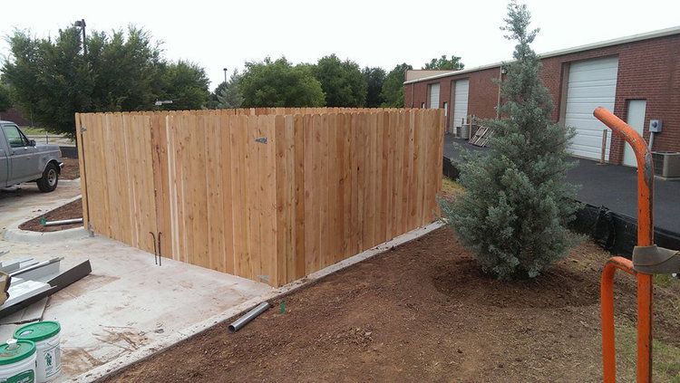 A wooden fence is being built in front of a brick building.