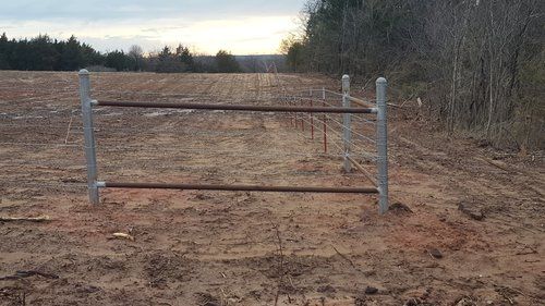 A metal fence is sitting in the middle of a dirt field.