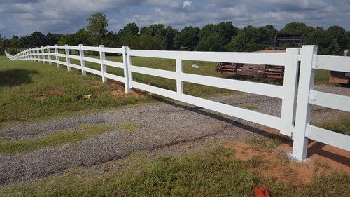 A white fence is sitting in the middle of a grassy field.