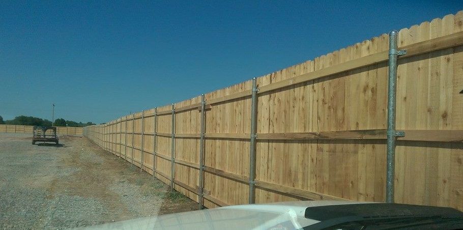 A wooden fence is sitting on the side of a dirt road.