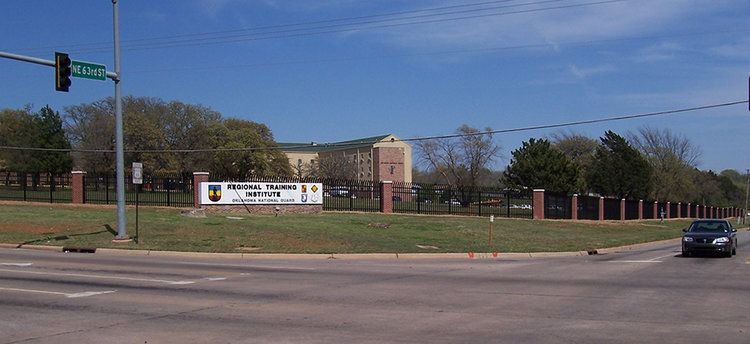 A car is driving down a street in front of a school
