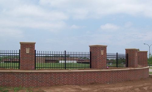 A brick wall with a metal fence surrounding it
