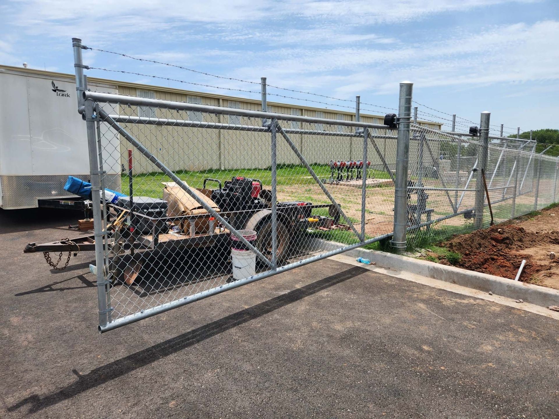 A chain link fence with a trailer parked in front of it.
