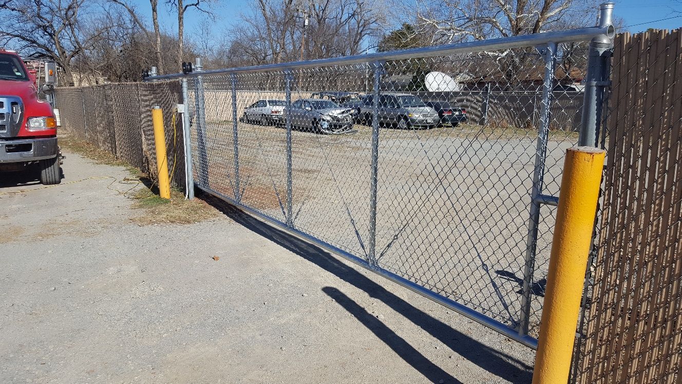 A chain link fence with a red truck parked behind it.