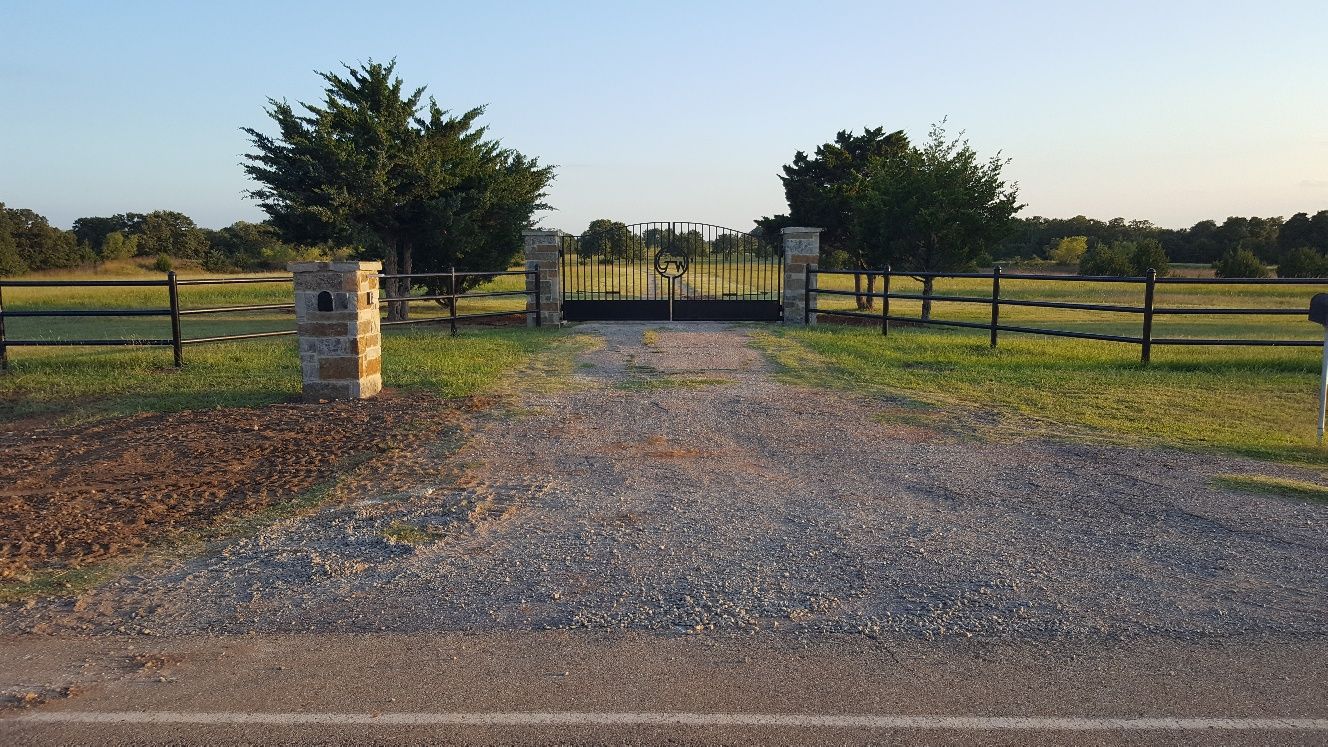 A gravel road leading to a fenced in area