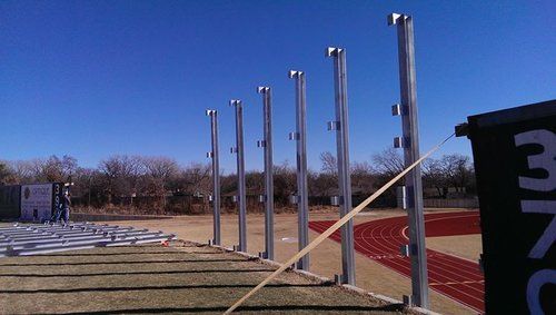 A row of poles are lined up in front of a track