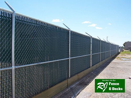 A chain link fence with a green slat covering it