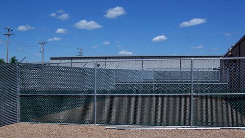 A chain link fence is surrounding a building with a blue sky in the background.