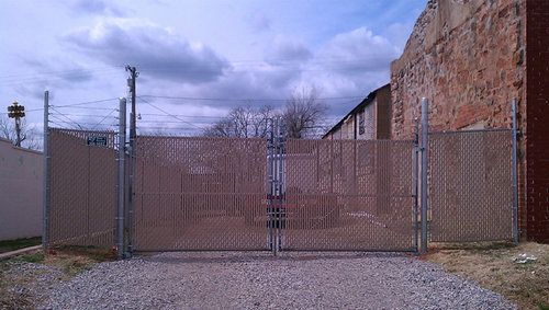 A chain link fence is surrounding a gravel road.