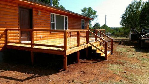 A log cabin with a wooden deck and stairs.