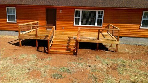 A wooden deck with stairs is in front of a wooden house.