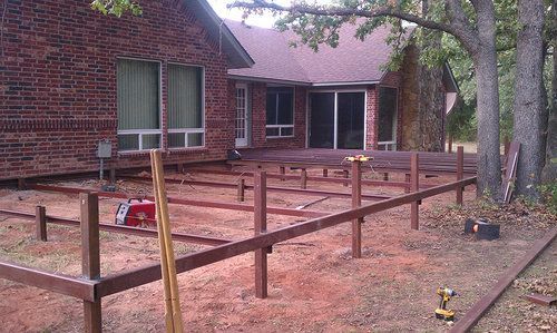 A wooden fence is being built in front of a brick house