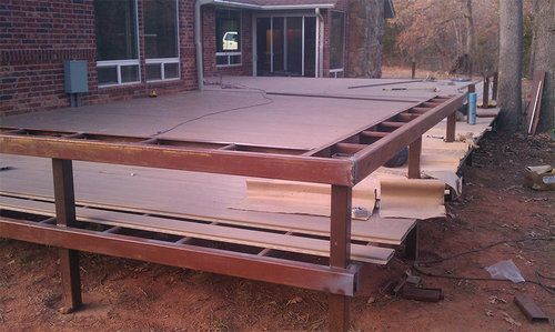 A wooden deck is being built in front of a brick house