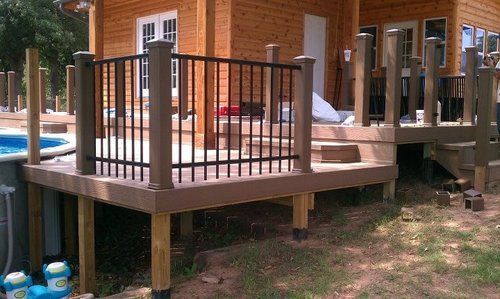 A wooden deck with a metal railing is next to a pool.