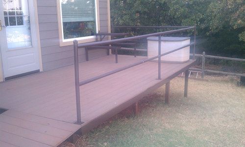 A wooden deck with a metal railing next to a house.