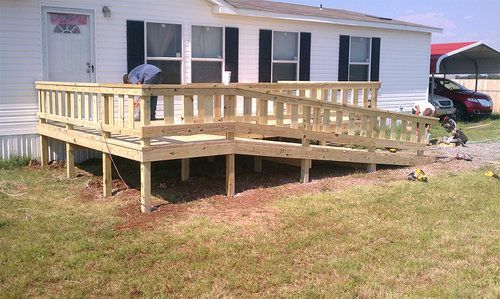 A mobile home with a wooden deck in front of it