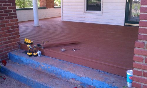 A wooden deck is being built in front of a brick house.