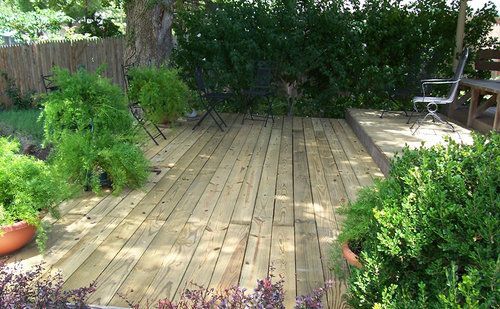 A wooden deck with chairs and plants on it
