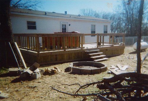 A wooden deck with stairs and a fire pit in front of a house