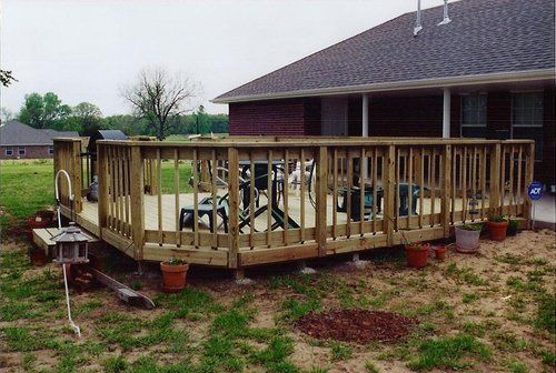 A large wooden deck in front of a brick house