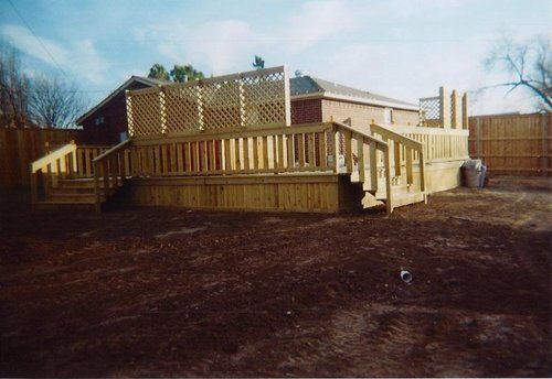A large wooden deck is in the backyard of a house