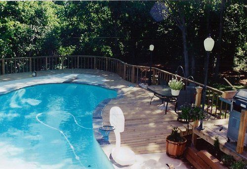 A swimming pool surrounded by trees and a wooden deck