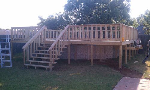 A wooden deck with stairs leading up to it in a backyard.