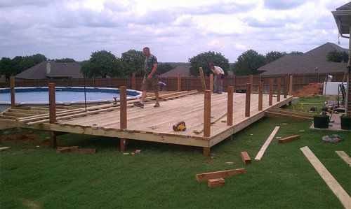 A wooden deck is being built next to a pool.