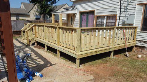 A wooden deck is being built in the backyard of a house.