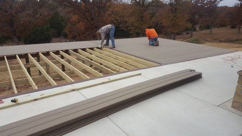 A couple of men are working on a wooden deck.