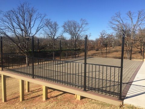 A deck with a fence around it and trees in the background