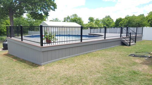 A large deck with a fence around a swimming pool.