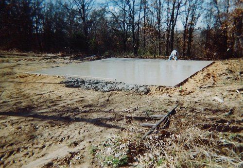 A large concrete slab is sitting in the middle of a dirt field.