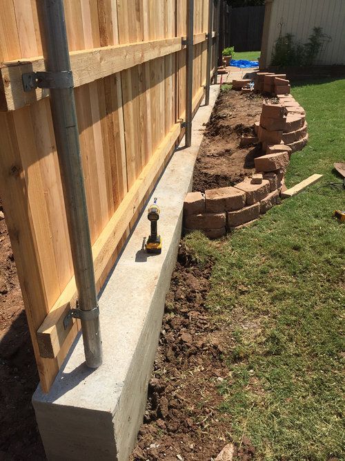 A wooden fence is being built in a backyard.