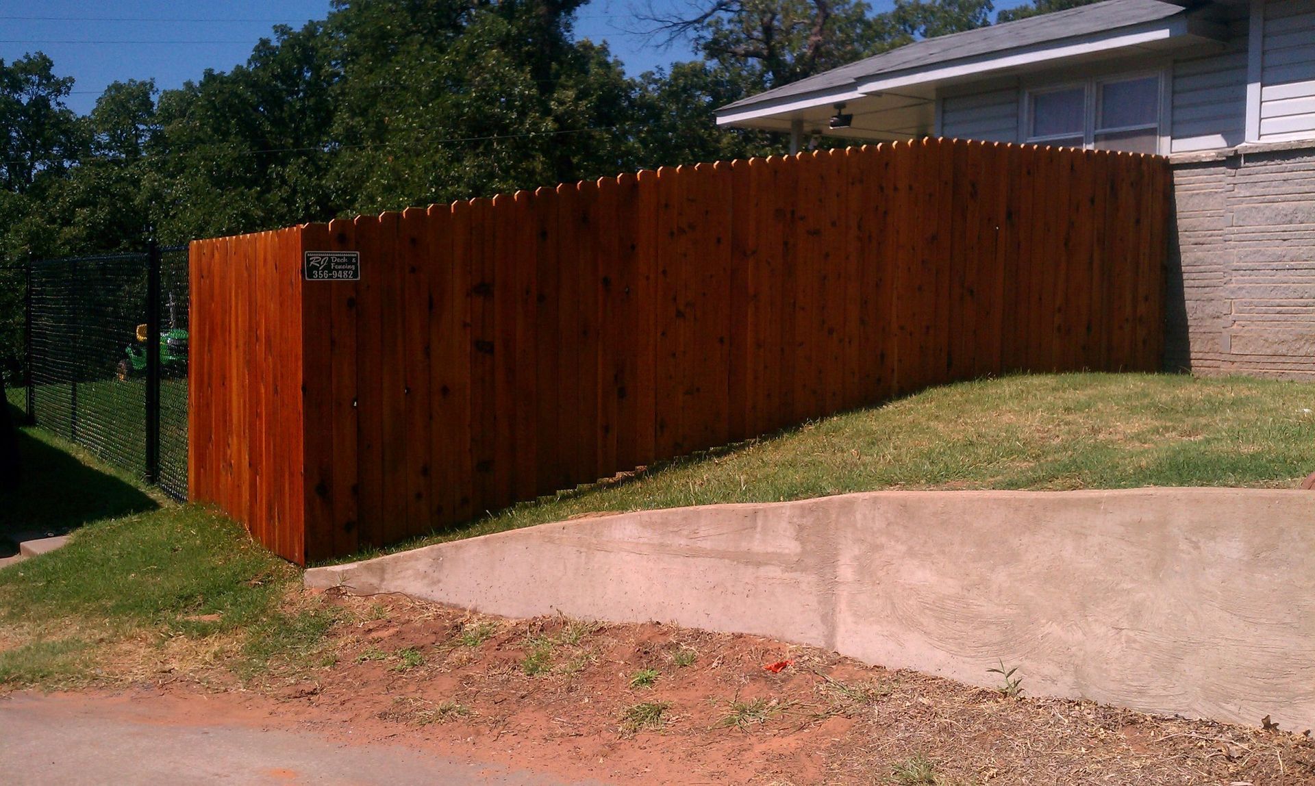 A wooden fence surrounds a driveway in front of a house.