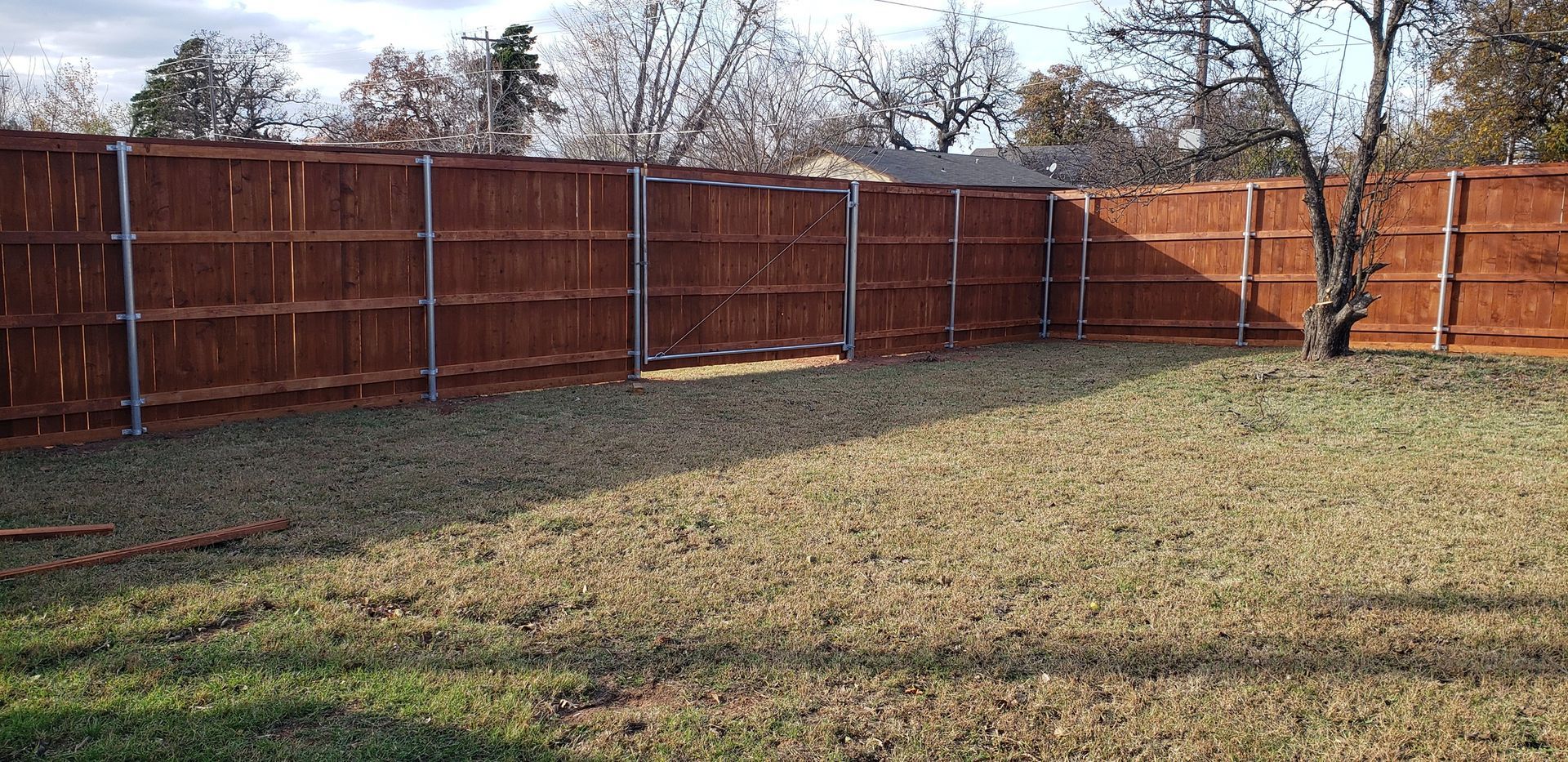 A wooden fence surrounds a lush green lawn in a backyard.