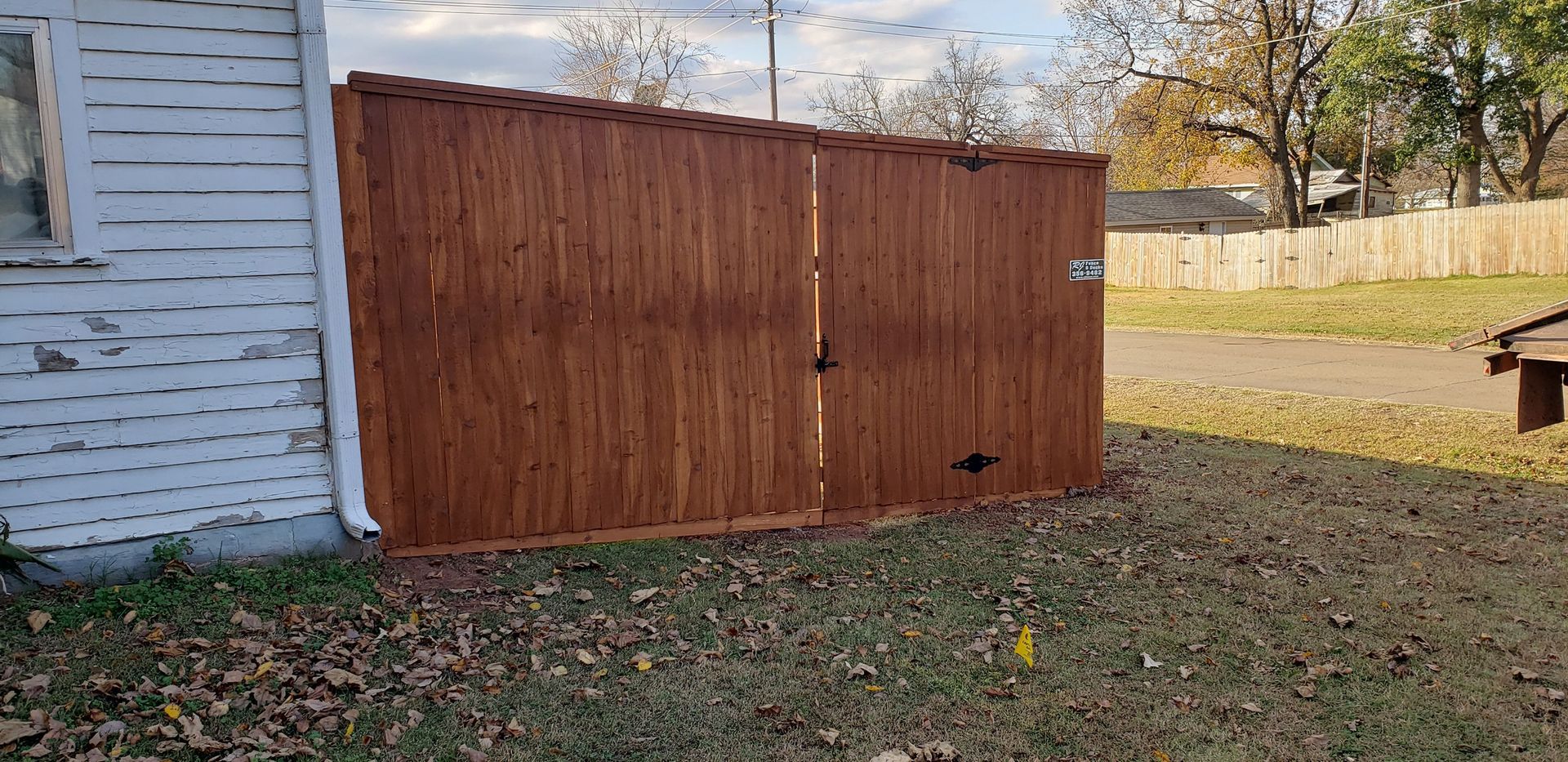 A wooden fence is sitting in front of a white house.