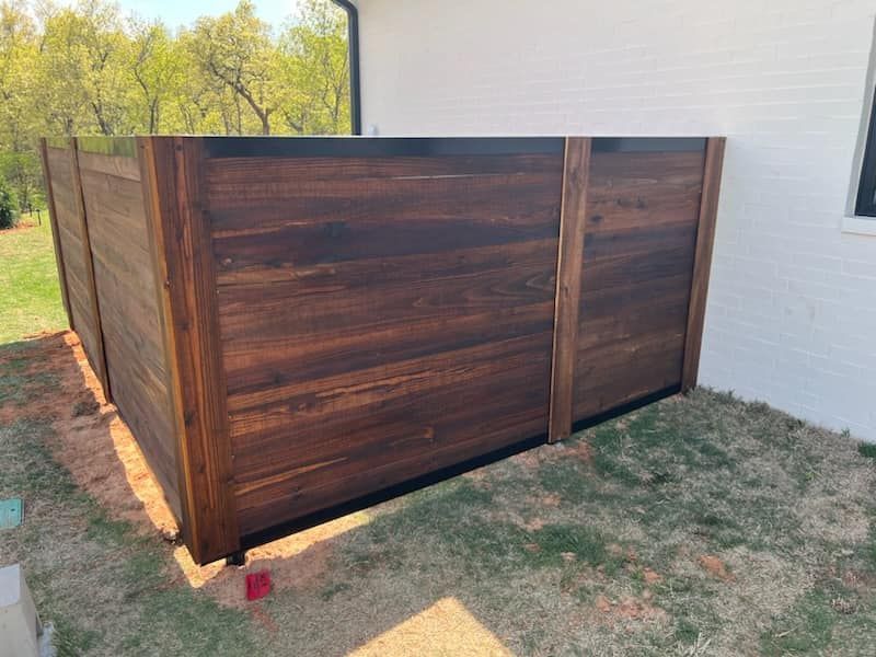 A wooden fence is sitting in the grass in front of a white house.