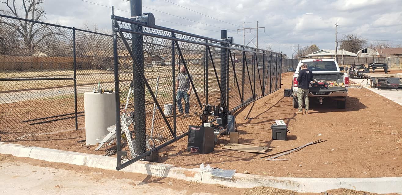 A chain link fence is being built on a dirt road