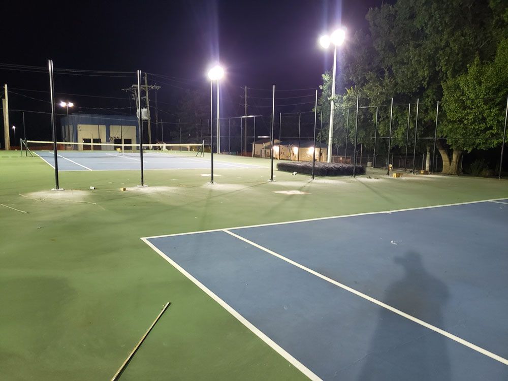 A tennis court that is lit up at night