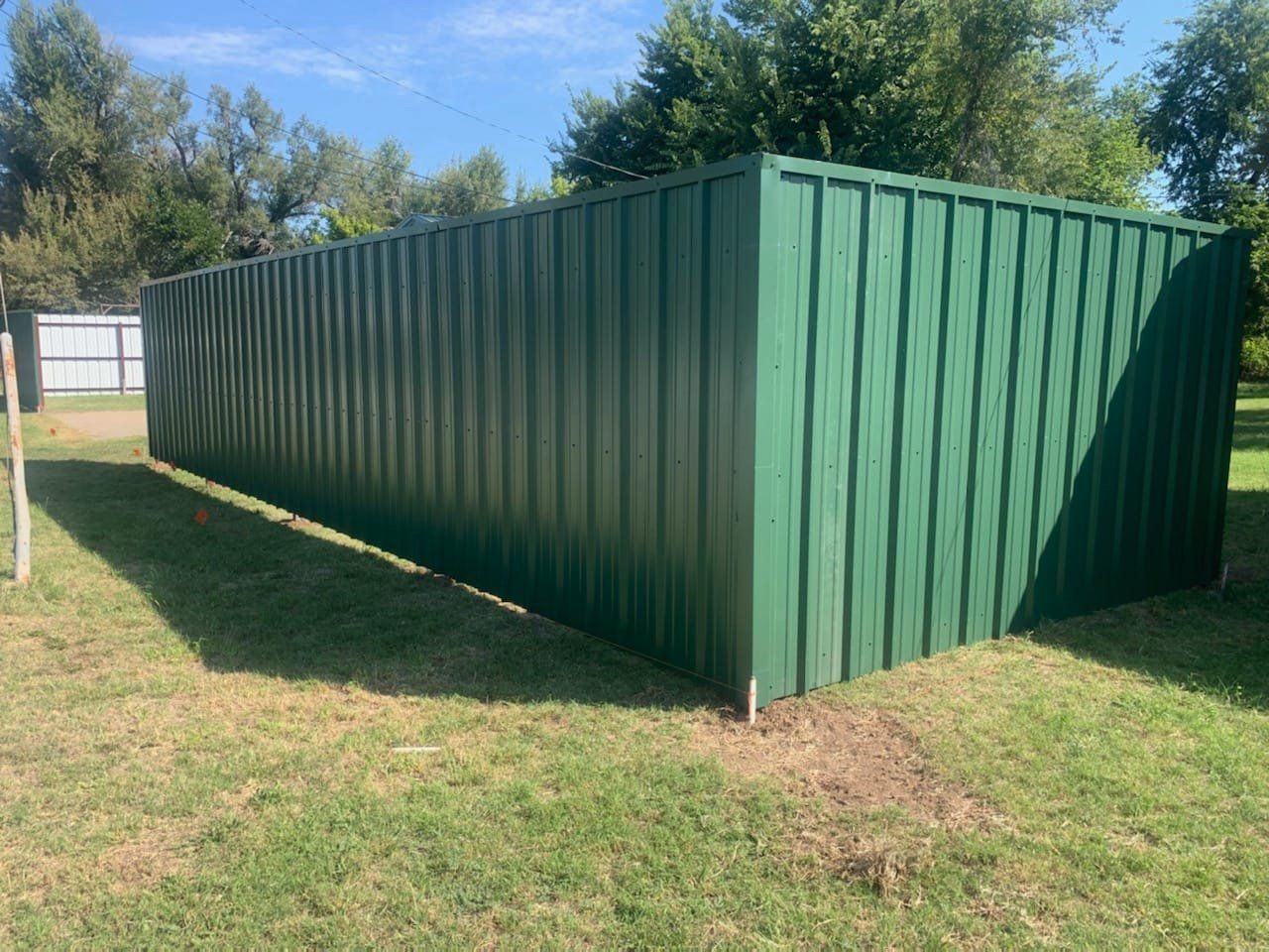 A green metal fence in the middle of a grassy field